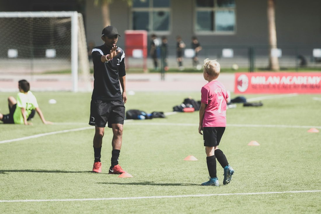 A coach instructing a young boy on a sports field, one-on-one